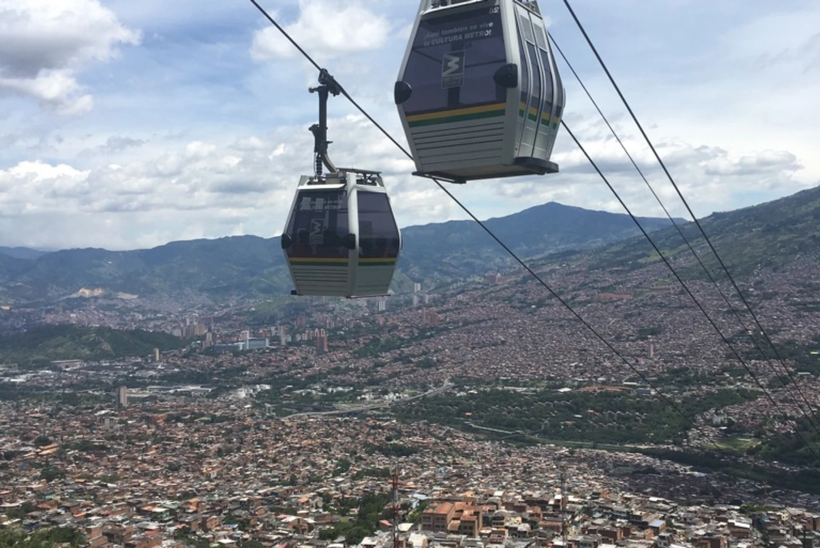 two cable cars over a city with mountains in the background