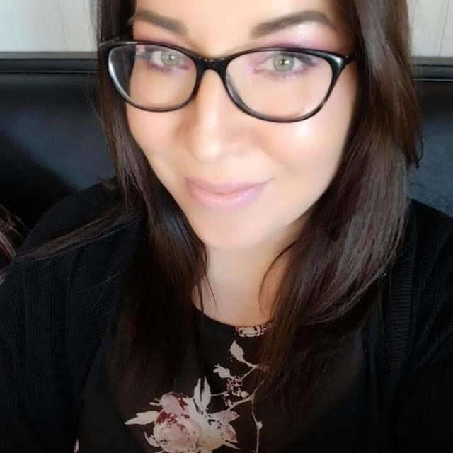 Fora Travel Agent Sarah Garcia wearing black rimmed glasses and a black floral shirt