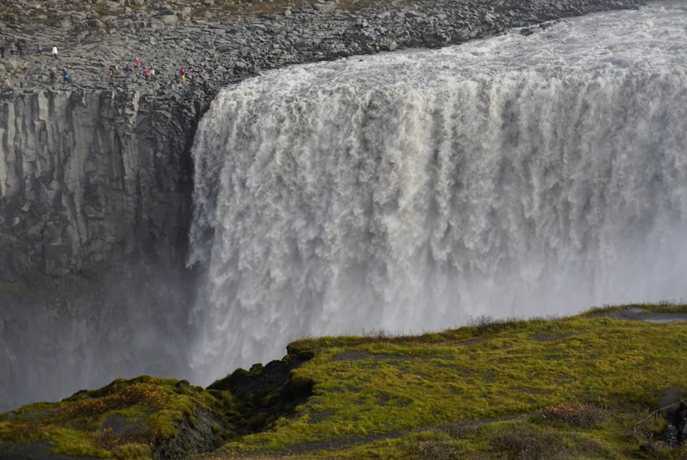 Waterfall next to rocky cliff during daytime
