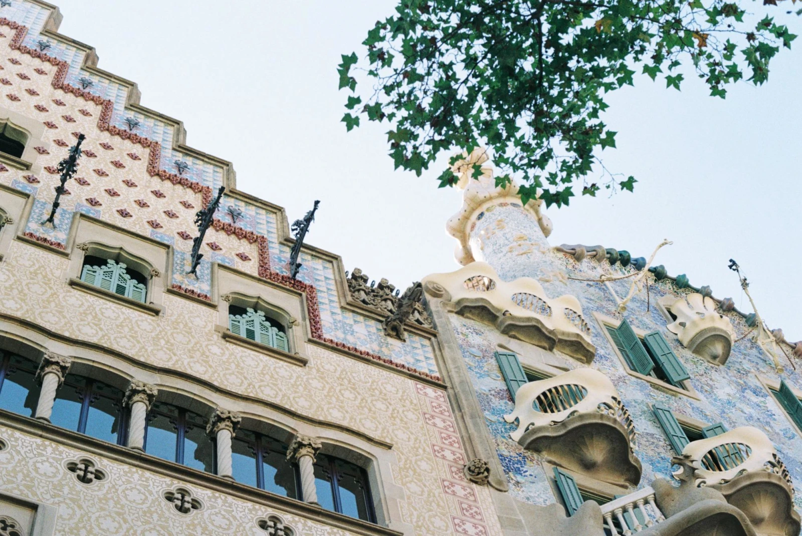 looking up an an ornate facade of a 2 buildings designed with tile and balconies 