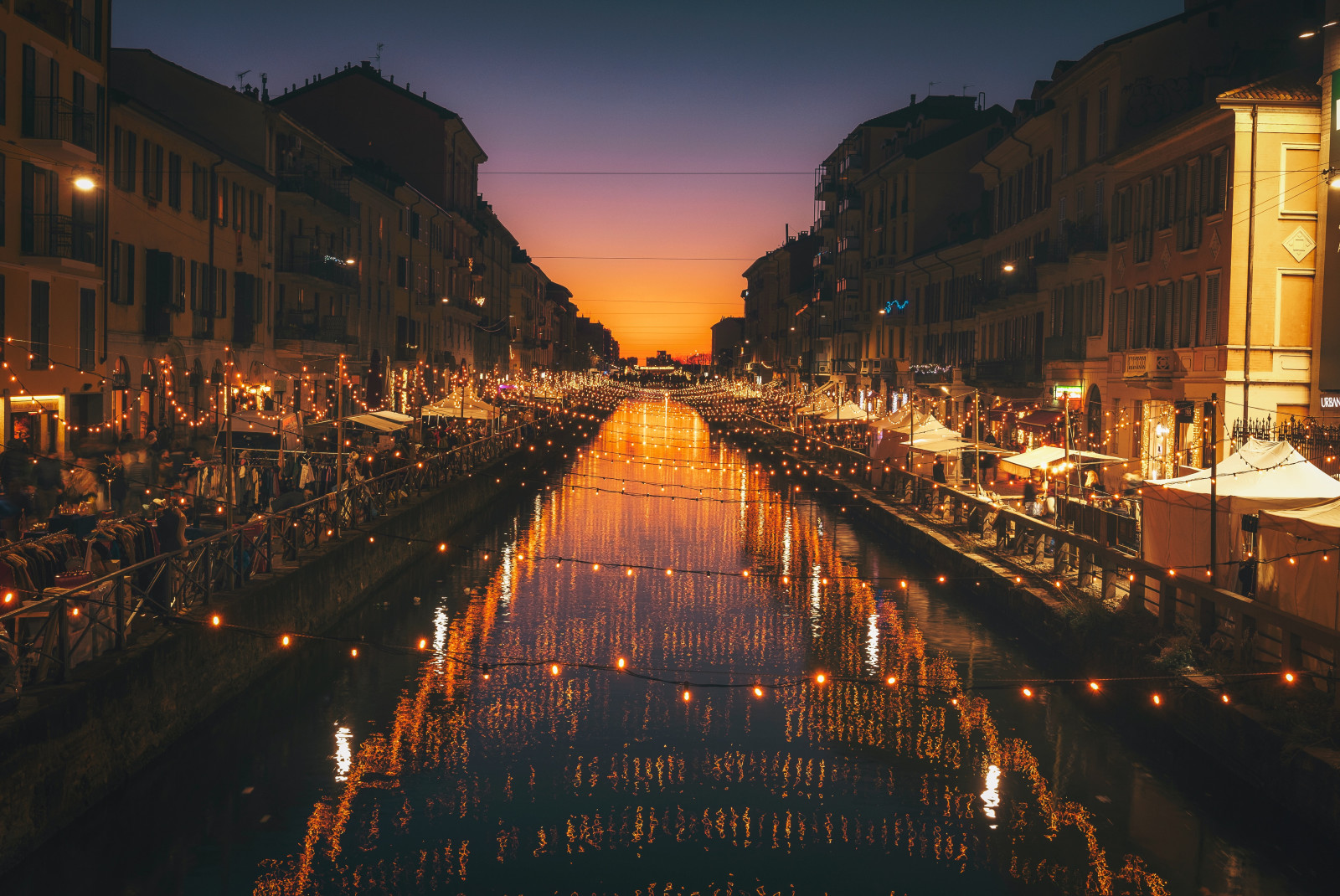 Orange string lights over a canal in Milan, Italy.