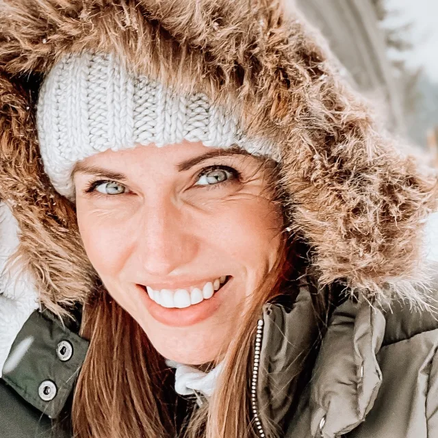 Travel advisor Lindsey Brainbridge smiles in a knit beanie and olive-colored winter hooded coat