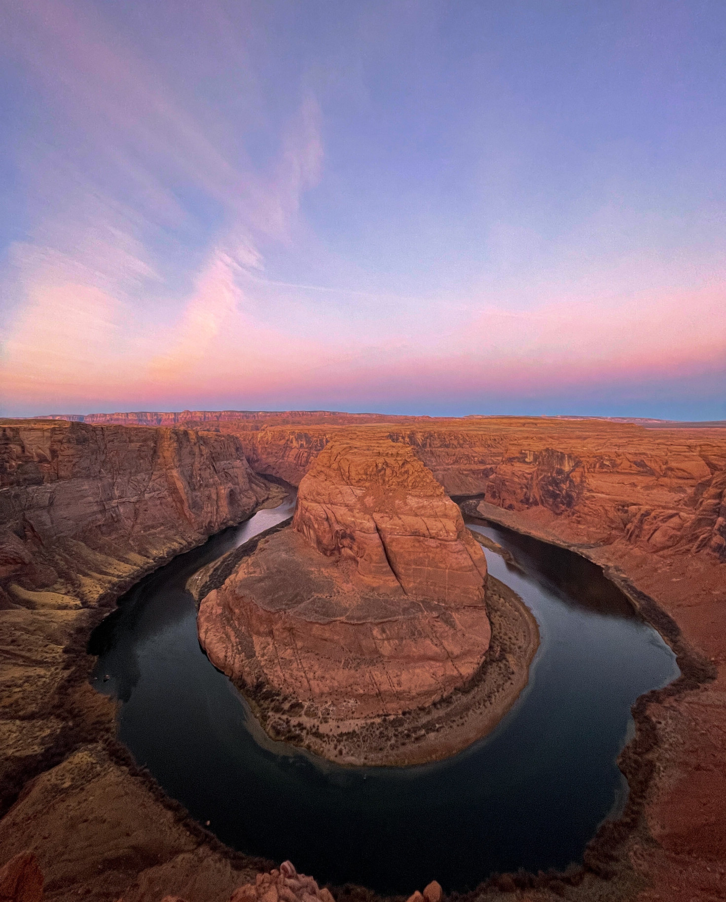 red rock surrounded by body of water during sunset