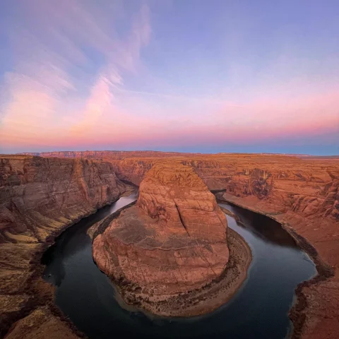 red rock surrounded by body of water during sunset