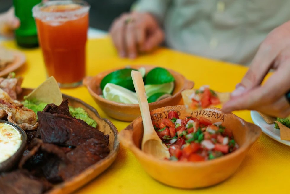 A yellow table with multiple bowls of food and orange drink.