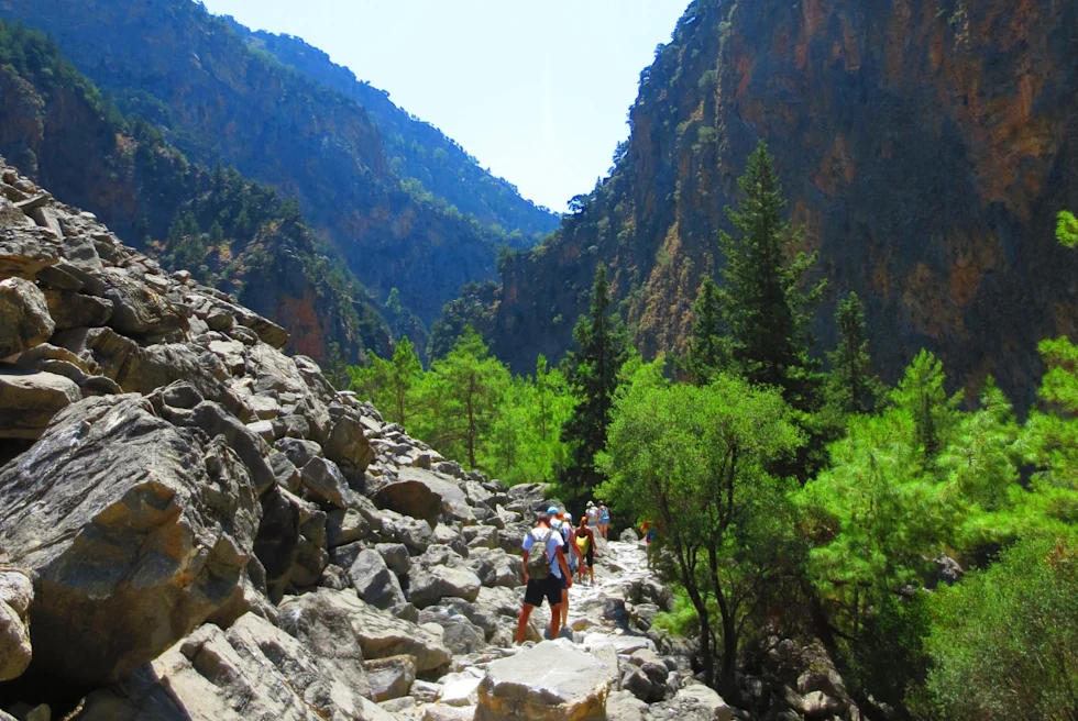 rocky trail between mountains with hikers in bright sunshine