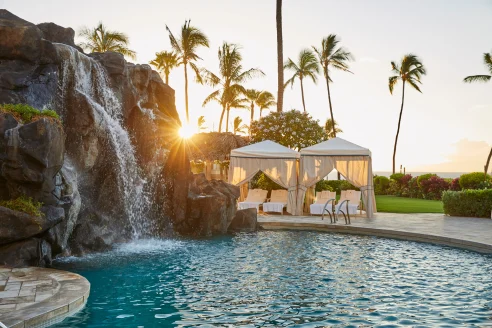 Poolside rock waterfall with cabanas