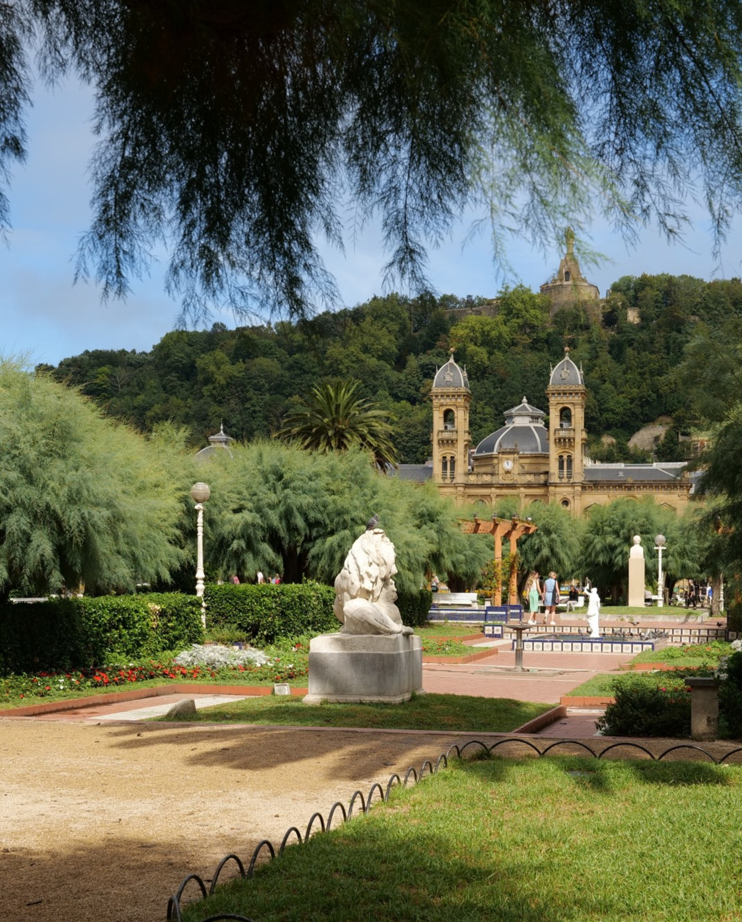 Park with Spanish style church with grass lawns and shade. 