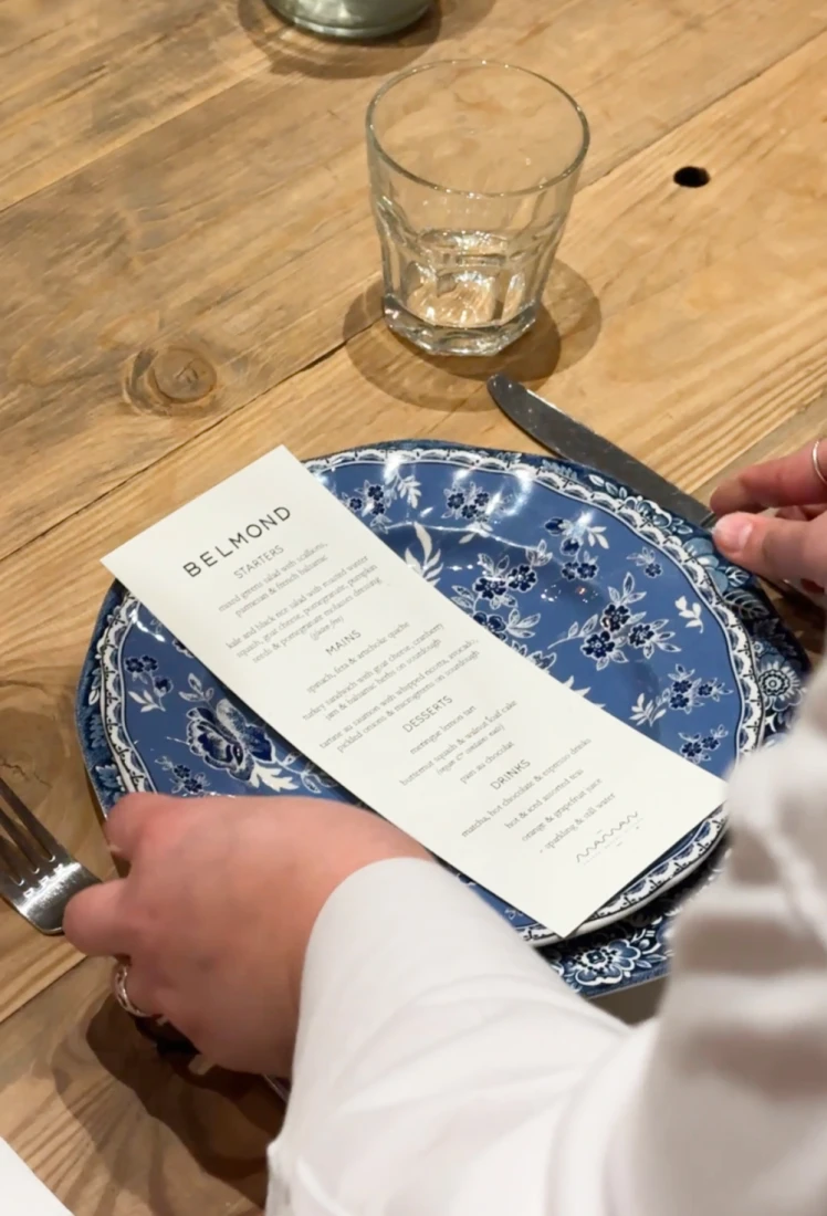 a white paper menu sits on a blue circular plate on a wooden table