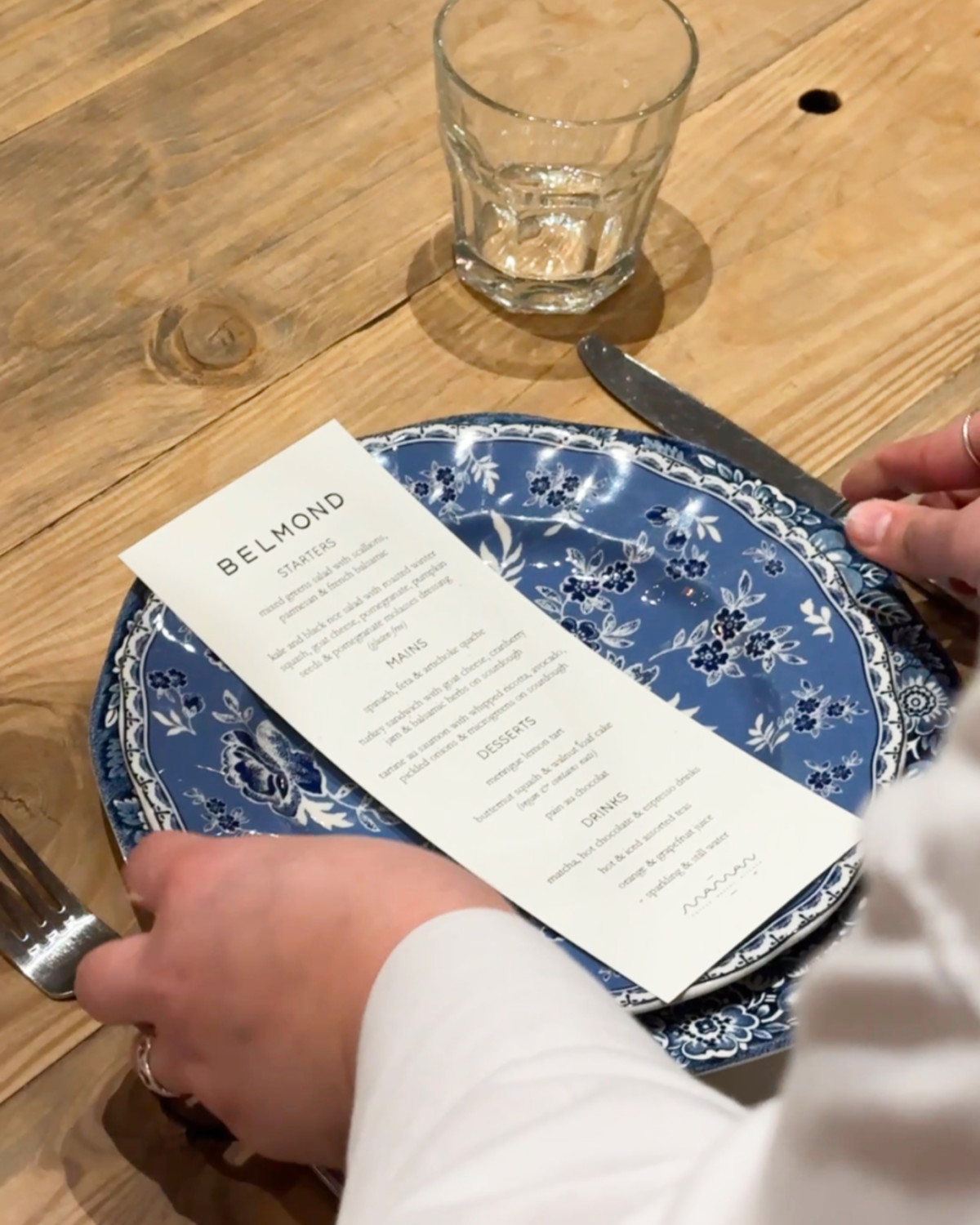 a white paper menu sits on a blue circular plate on a wooden table