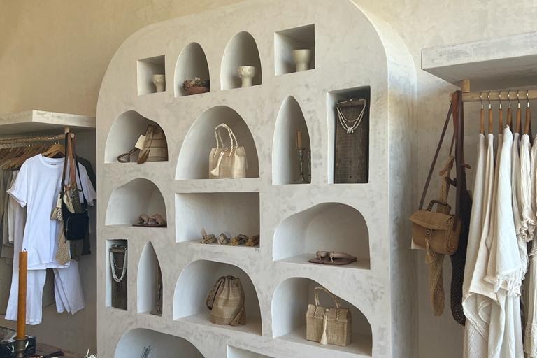 A white closet with clothes and handbags in it.