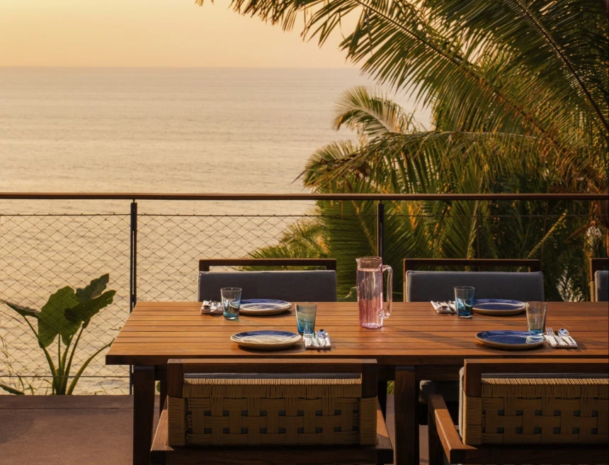 wooden table wth chairs overlooking the ocean