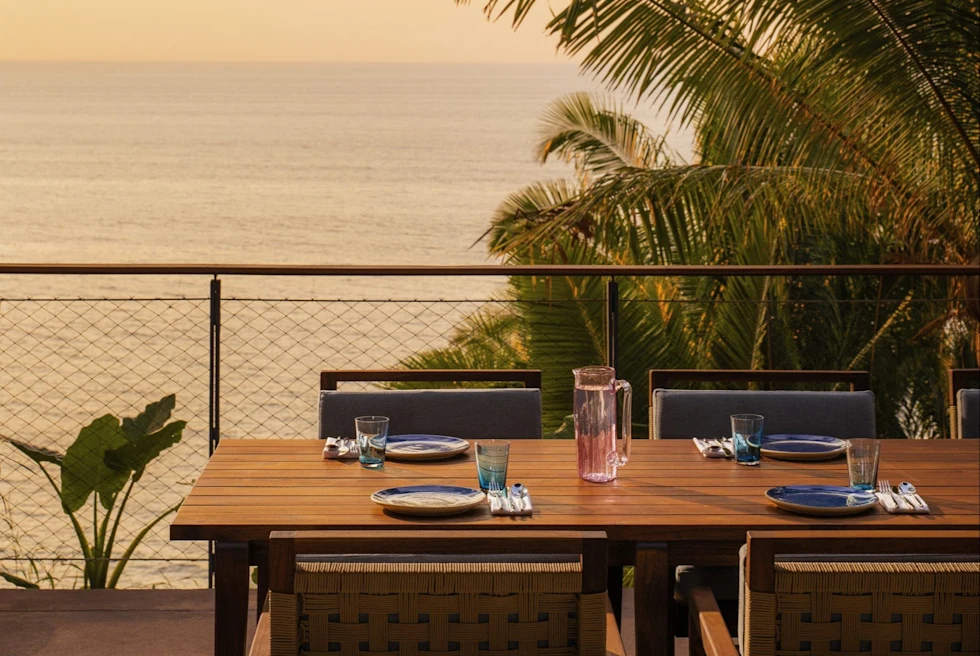 wooden table wth chairs overlooking the ocean