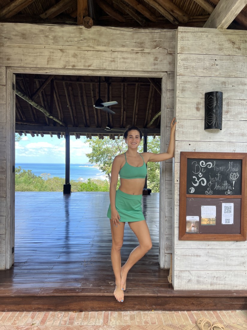 Travel advisor Emily standing in the doorway of an open area with a straw roof overlooking the beach