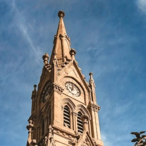 Large brown clocktower building under blue sky