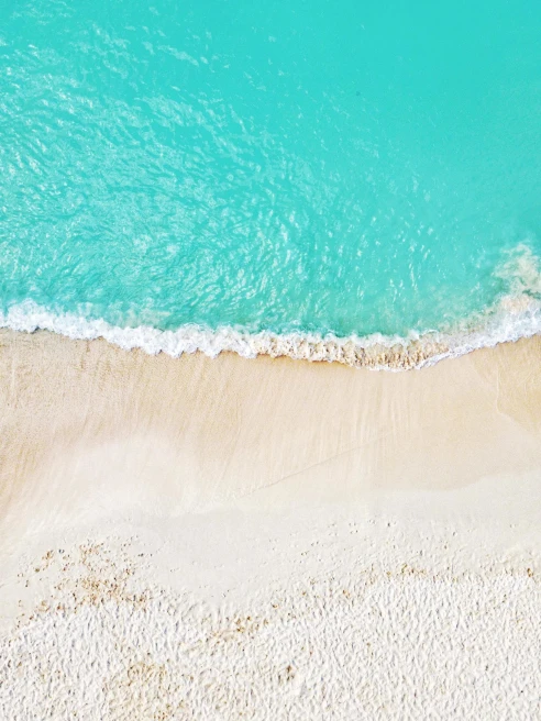aerial view of pristine blue water and white sand beach 