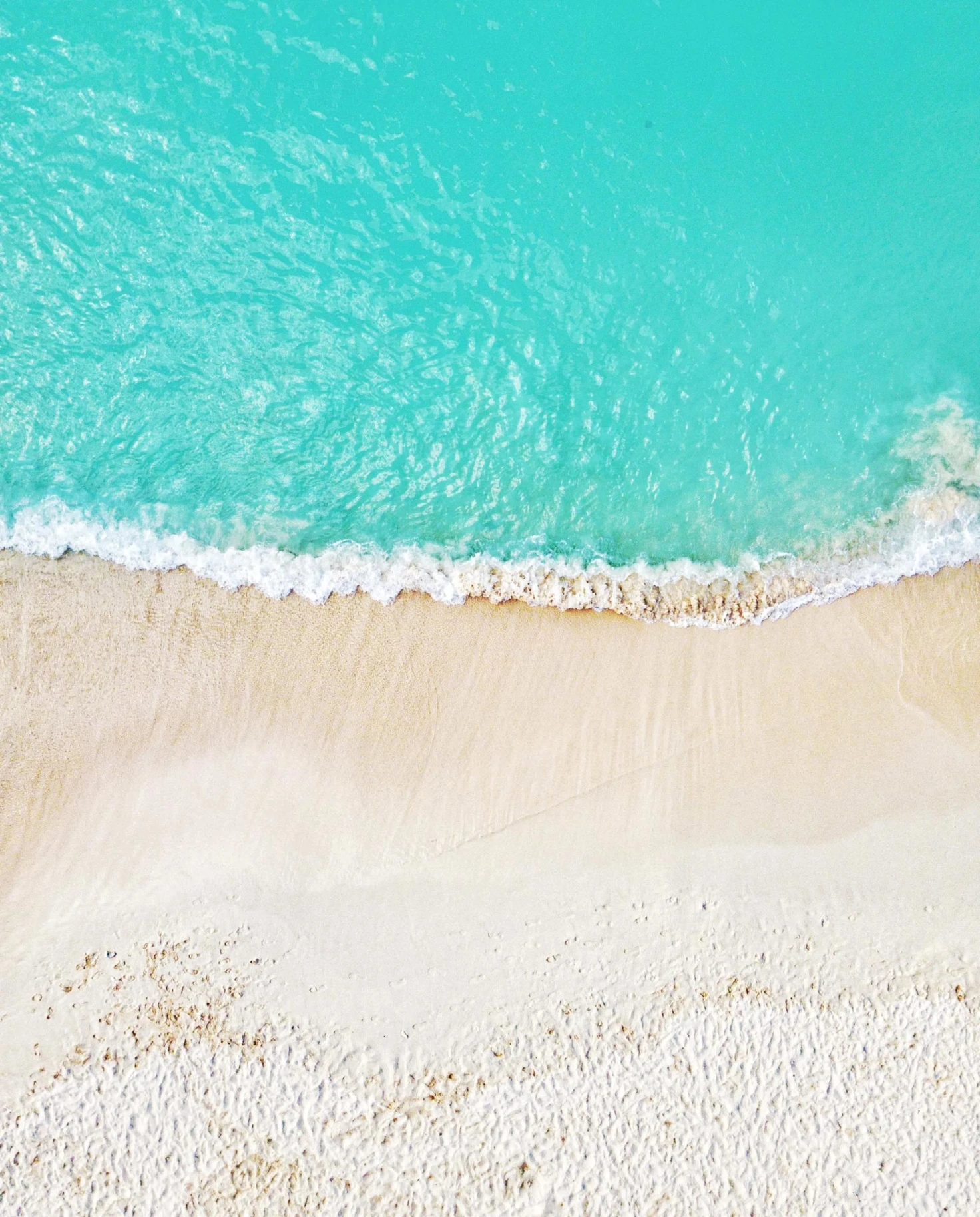 aerial view of pristine blue water and white sand beach 