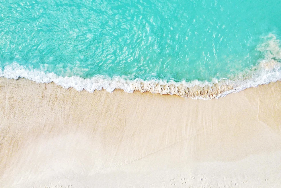 aerial view of pristine blue water and white sand beach