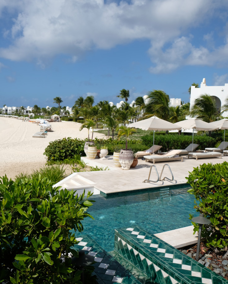 chairs next to pool with beach in the distance