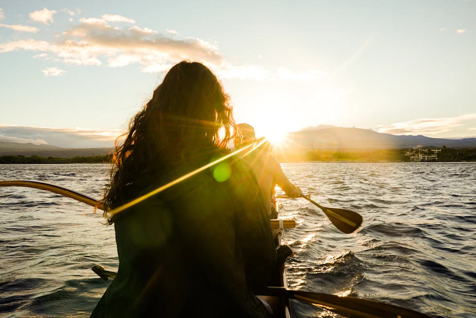 people in a canoe during sunrise