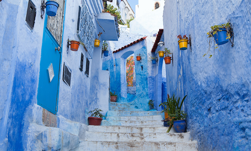 Morocco blue streets with colored flower pots and white staircase
