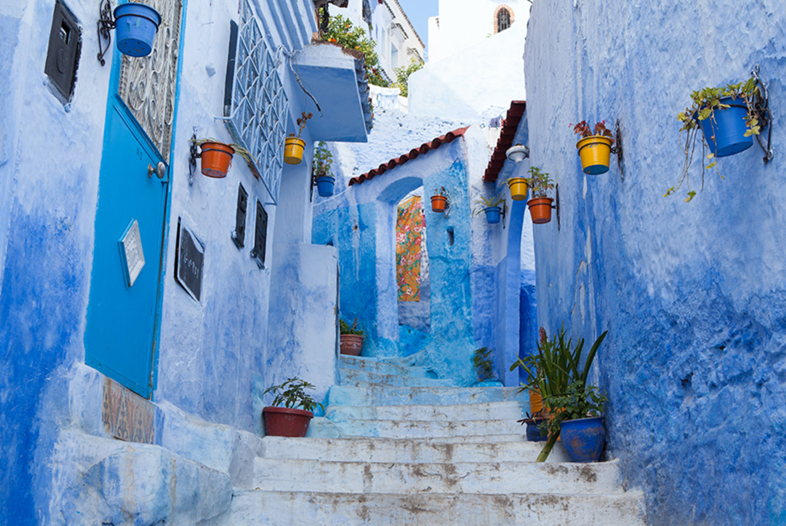 Morocco blue streets with colored flower pots and white staircase