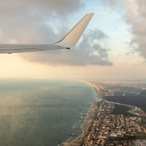 View from above of a plane flying over the ocean and hotels by Rome Airport Italy.