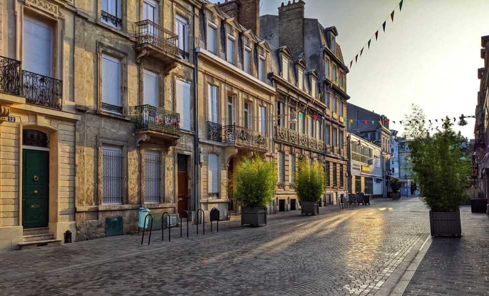 a quiet cobblestone plaza at sunset with tables and chairs