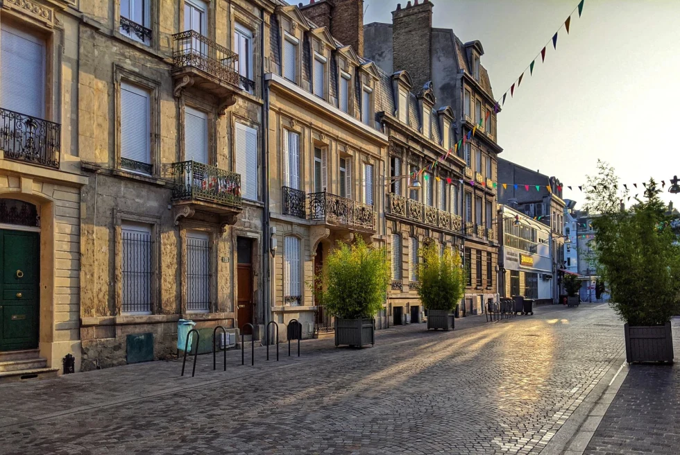 a quiet cobblestone plaza at sunset with tables and chairs