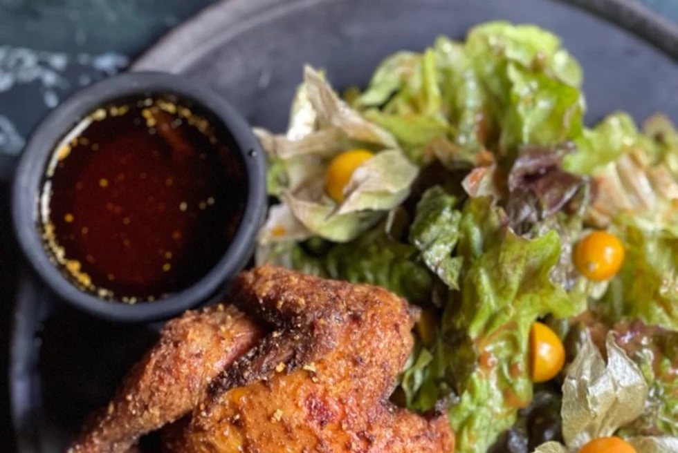 meal of fried chicken, salad and a dip on a black ceramic plate