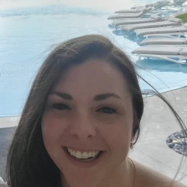 Travel advisor Lauren Taylor with dark brown hair smiling in front of a pool