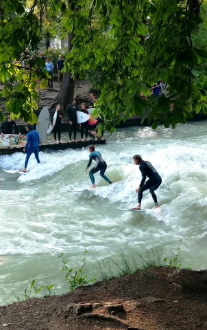 A picture of three people surfing in the water during the daytime.