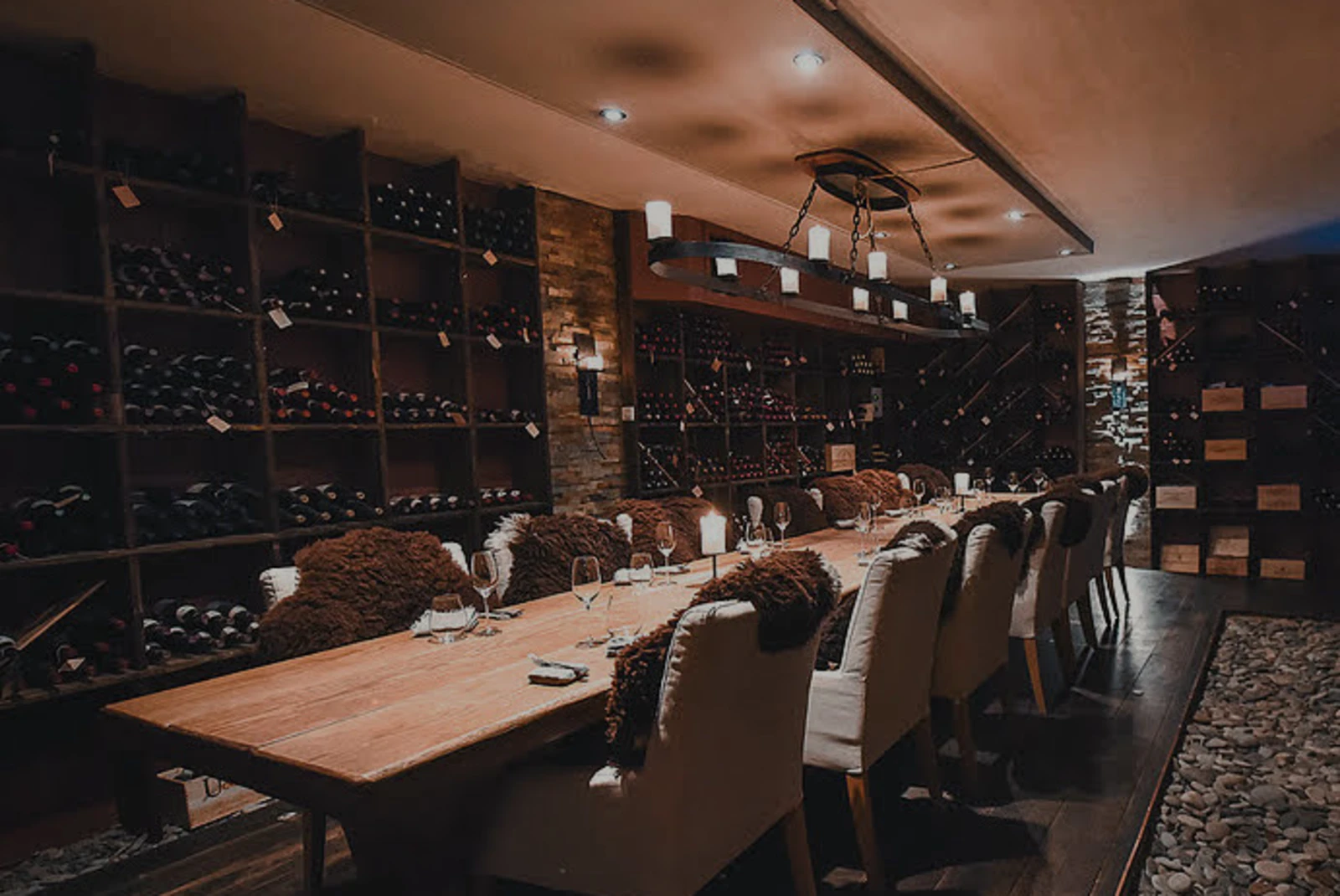 Wood table with chairs and wine bottles in a dimly lit room