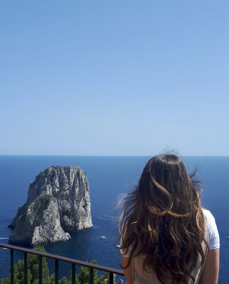 Girl standing in front of sea and rock. 