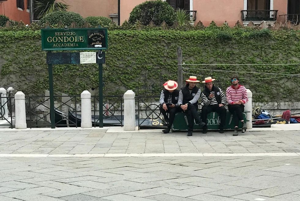 Four persons in striped shirts sitting on a bench.