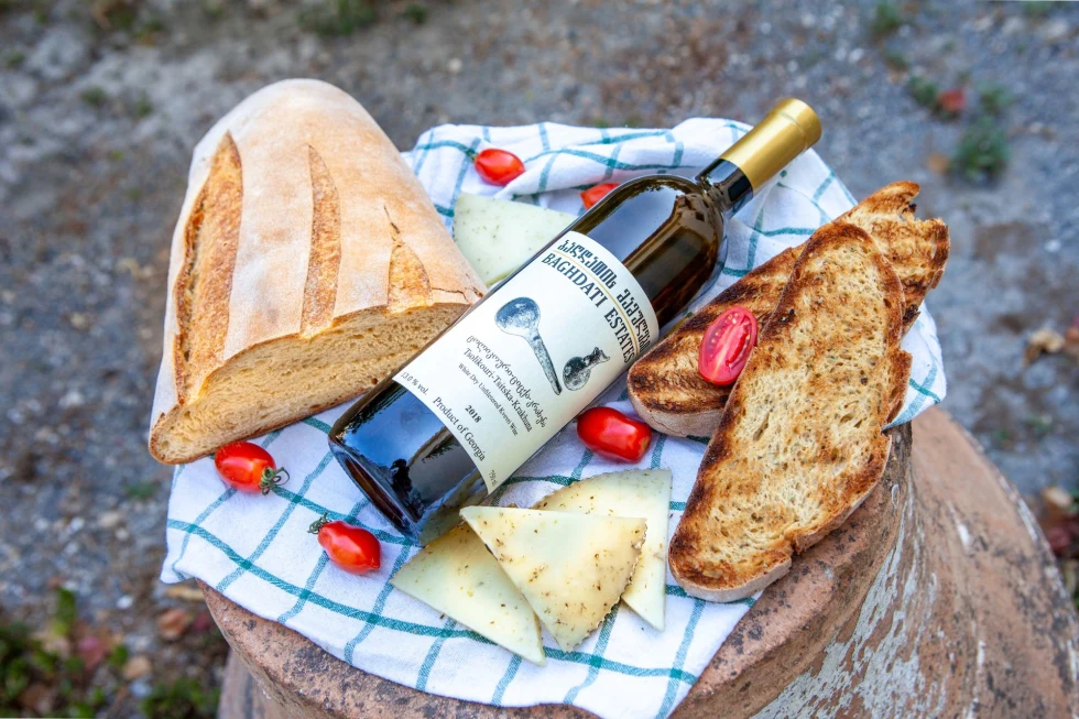 wine, a loaf bread, tomatoes on a wood stump 