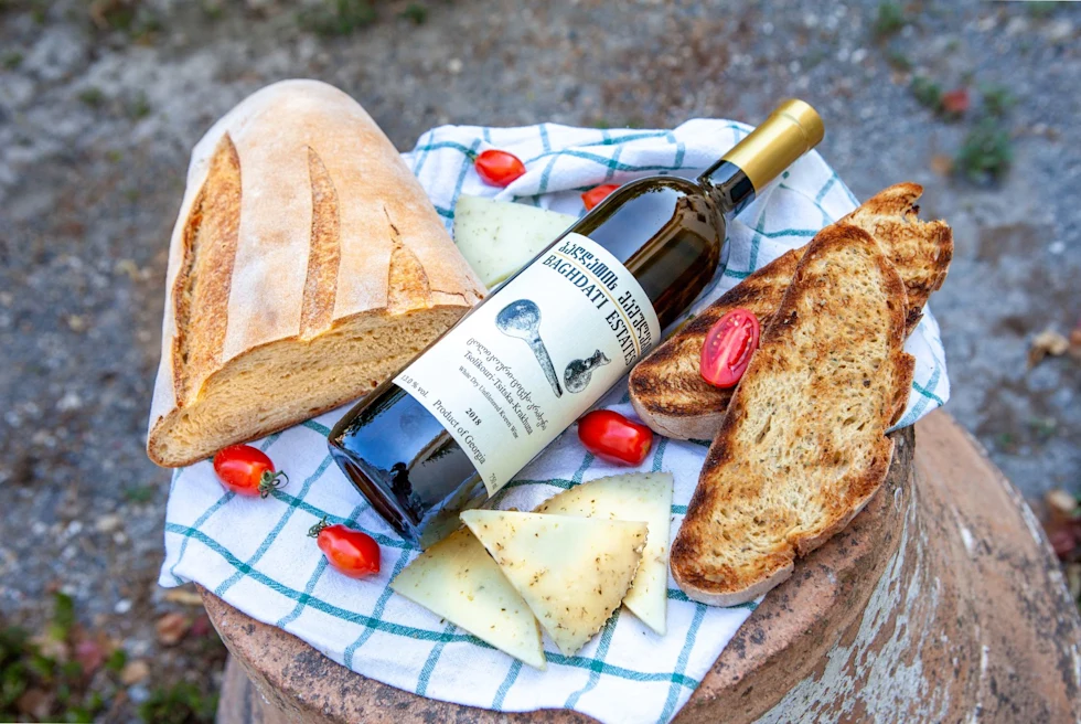 wine, a loaf bread, tomatoes on a wood stump