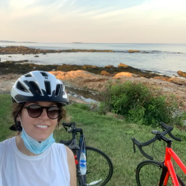Travel Advisor Courtney Loomos in front of two bikes at sunset with a body of water.
