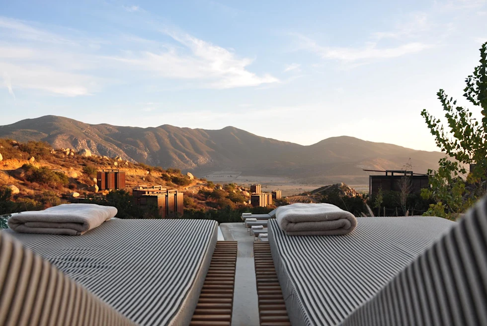 lounge chairs with towels look out over dessert valley at sundown