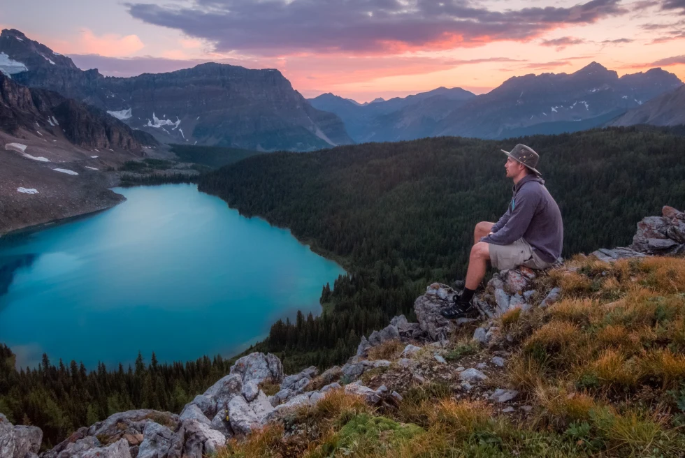 Man sitting on a rock looking at the mountains.