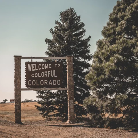 A picture of a wooden welcome sign that reads "Welcome to Colorful Colorado" during daytime.