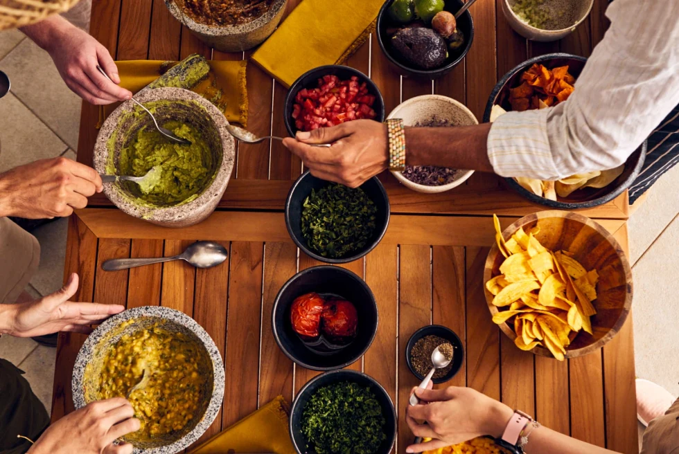 wooden table with bowls of guacamole and salsas
