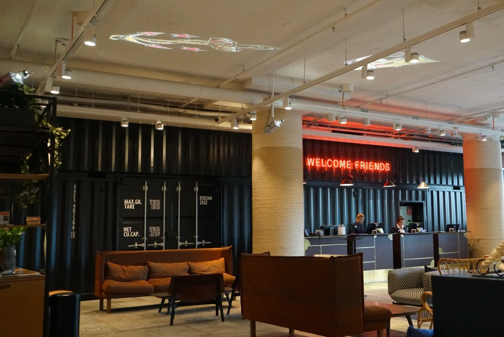 A hotel lobby with dark colors and a neon sign. 