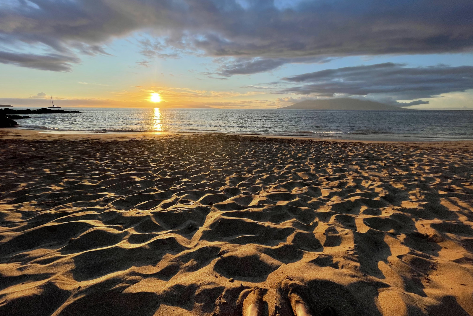 Sandy beach next to body of water during sunset