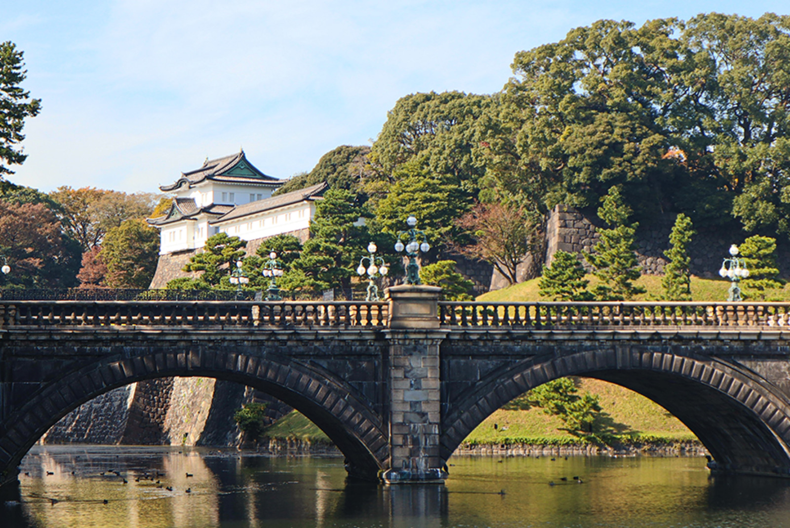 bridge in Japan with temples and tall green trees with hills and a lake