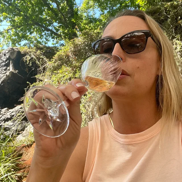 Travel Advisor Joy Cravens sips a glass of rose wearing black sunglasses