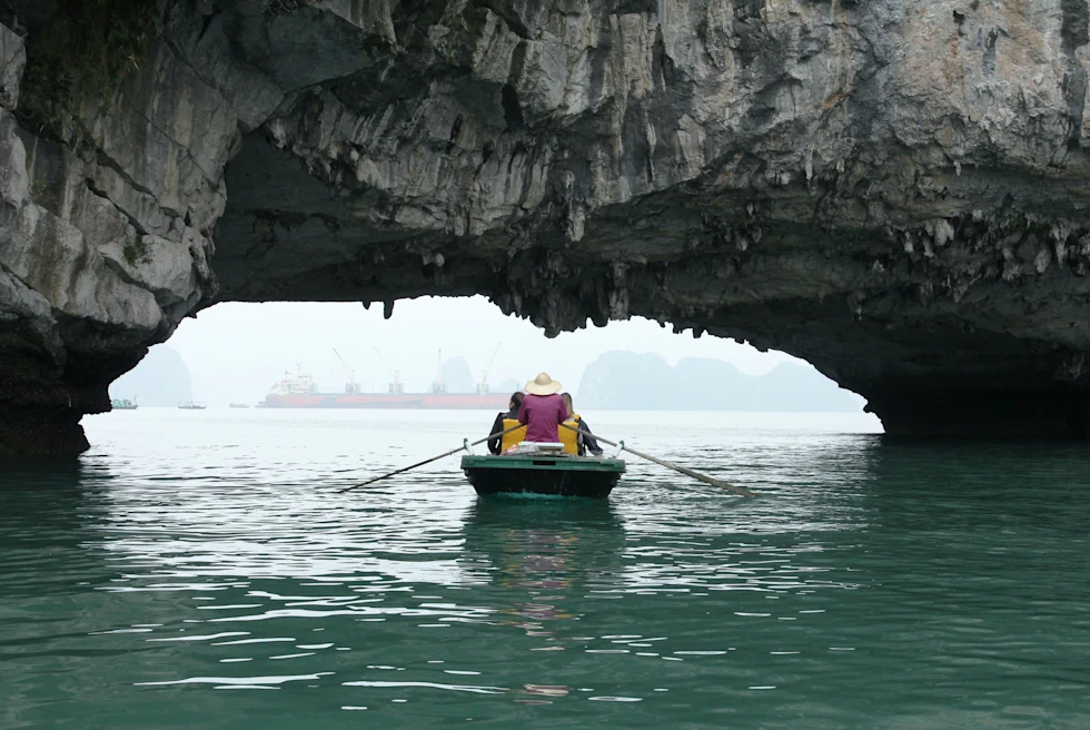 a small boat goes under low rock opening