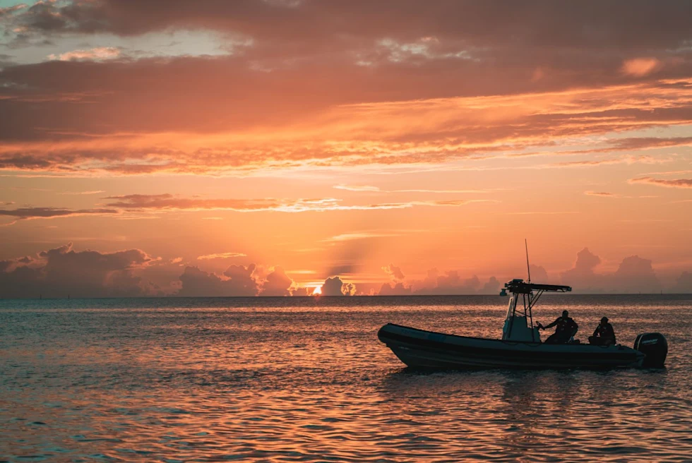 pink orange and purple sunset reflected in ocean water with boat floating