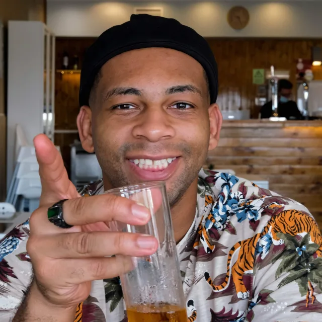 Travel Advisor Isaiah S. Brown in a black hat, tiger shirt and holding a glass.
