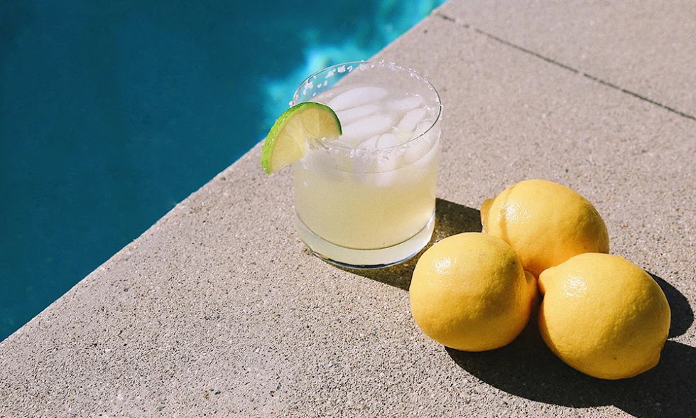 A cocktail with a lime sitting next to a pool in Palm Springs, California. 